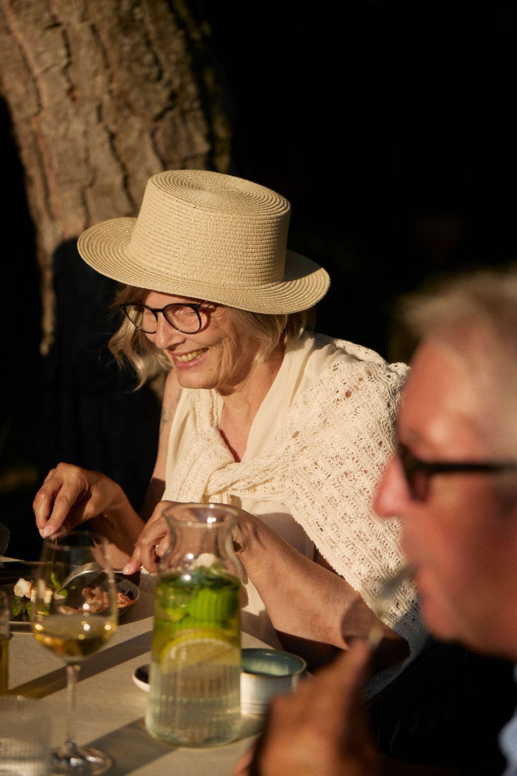 Menschen sitzen um einen runden Grilltisch, kochen gemeinsam und genießen die Atmosphäre im Freien.